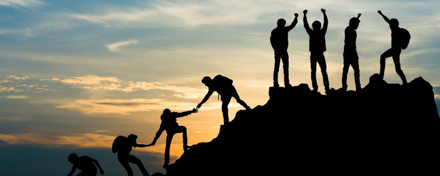 Silhouette of team summitting a mountain during sunset