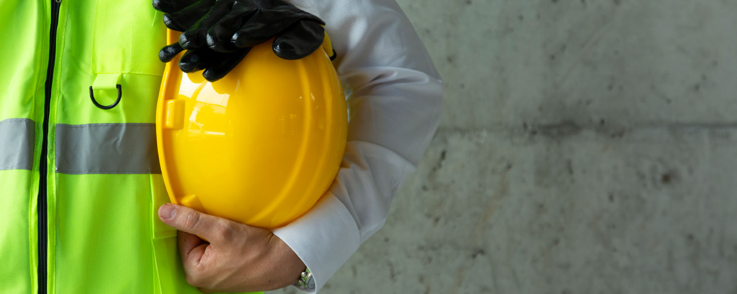 Worker holding a hard hat and rubber gloves