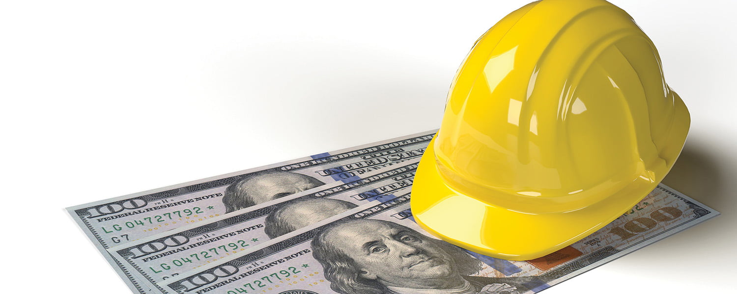 Yellow hard hat on top of US dollar bills