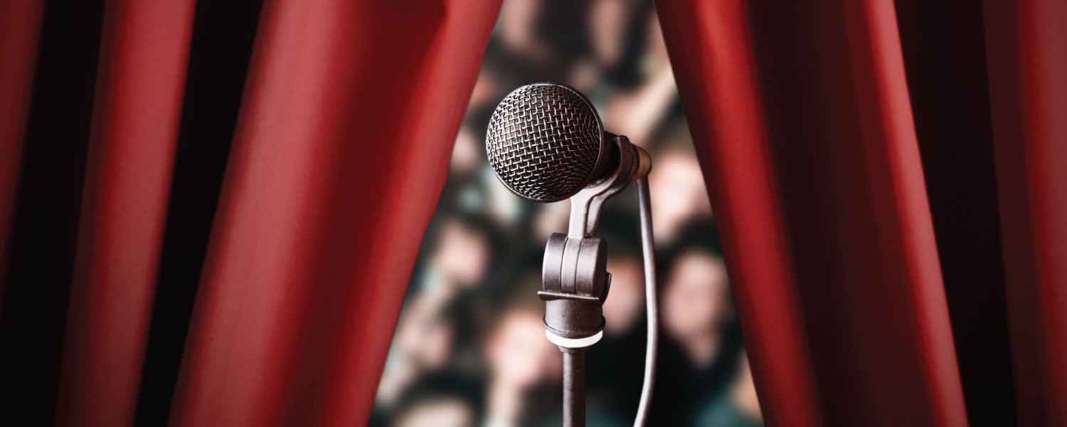 Microphone in front of an audience and a red curtain